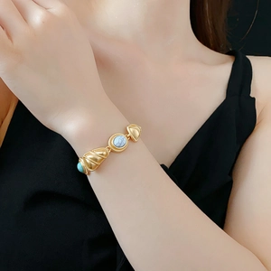 Close-up of vintage gold bracelet with white marble stone and turquoise accents on wrist