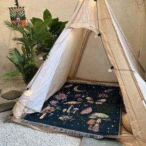 Detail of woven camping blanket with mushroom and butterfly patterns and white fringe