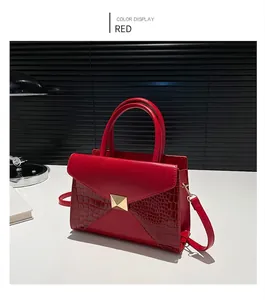 Detail of red tote bag featuring smooth leather and crocodile texture with a gold buckle