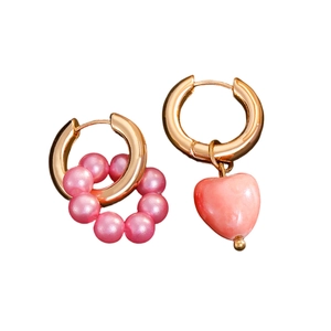 Asymmetric gold hoop earrings with pink pearls and heart pendant on white background