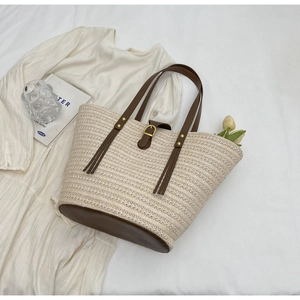 Detail of woven straw texture and premium brown leather handles on a summer tote bag