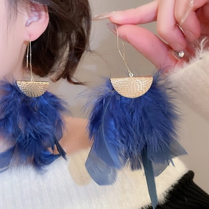 Detailed view of long navy blue feather tassel earrings with hammered gold metal accents