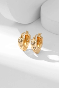 Macro view of gold-plated U-shaped earrings featuring star-shaped patterns and zircons