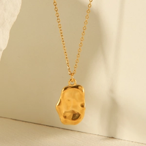Detailed view of irregular gold pendant with natural texture on a fine link chain