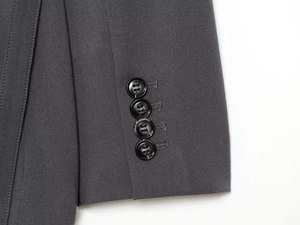 Detail of dark grey suit jacket sleeve with four black buttons and high-quality fabric