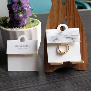 Folded marble jewelry display card with gold ring on a cute wooden bear holder