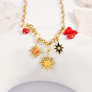 Bohemian gold necklace with sunflower, black star, and red heart charms on a white ring