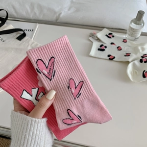 Detail showing two pairs of pink cotton mid-calf socks with heart and strawberry patterns