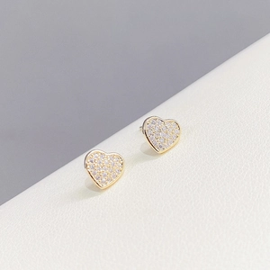 Detailed macro view of heart-shaped gold studs with micro-paved sparkling crystals