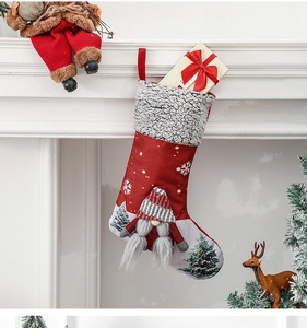 Close-up of a festive Christmas stocking with a grey gnome and gift box by a fireplace
