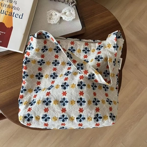 Detail of vibrant flower embroidery on off-white linen tote bag with simple wish tag