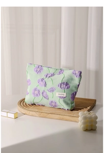 Close-up of floral embroidery on light green canvas makeup bag with H&R label