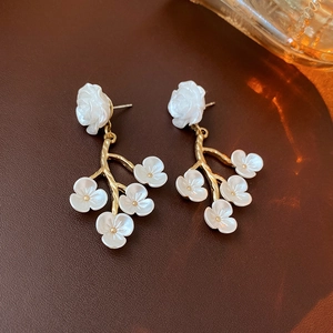 Detailed macro shot of vintage gold flower earrings with white petals on leather surface