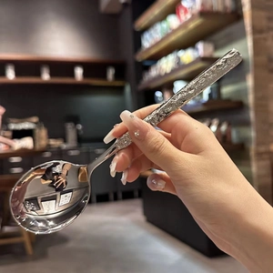Polished stainless steel spoon with embossed stone texture handle shown in hand