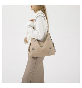 Detail of beige nylon tote bag featuring silver bow charms and stylish chain strap