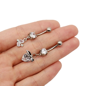 Détail de piercings de nombril argentés avec pendentif cœur et feuille et zircons clairs