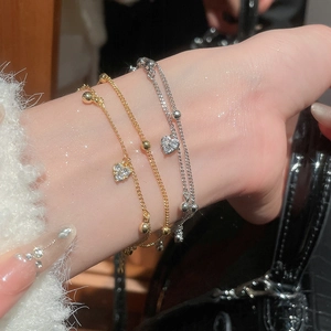 Detail of 18k gold and silver layered heart charm bracelets with zircon stones