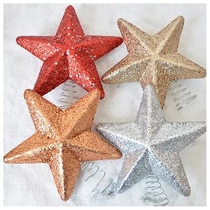 Detailed view of four glittery Christmas tree star toppers in gold, red, and silver
