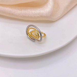 Minimalist geometric spiral ring in gold and silver finish on a clean ceramic display