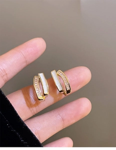 Detail of gold-plated U-shaped earrings with white enamel and shimmering cubic zirconia