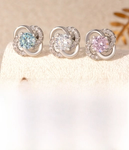 Macro view of clover-shaped stud earrings in blue, pink, and white zirconia stones