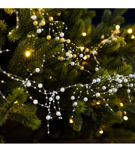 Detail of white and gold Christmas pearl bead garland on tree with warm lighting