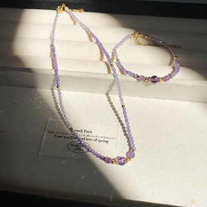 Macro shot of purple faceted beads and gold accents on a jewelry set in sunlight