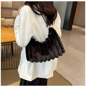 Modella che indossa una borsa in peluche nera con trama a coste plissettata e tracolla
