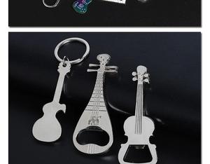 Detail of silver guitar keychain and violin bottle openers on a black background
