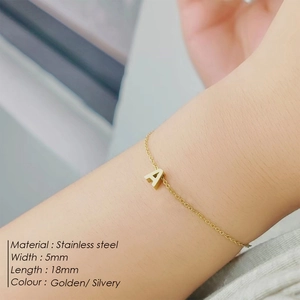 Gros plan d'un pendentif initiale A de 5mm en acier inoxydable doré sur un bracelet fin