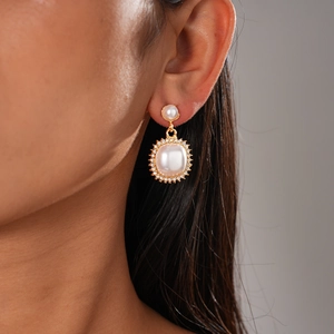 Detail of elegant gold pearl drop earring with rhinestones on model's ear profile