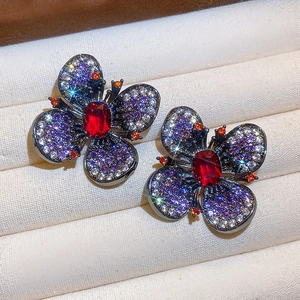 Dettaglio ravvicinato di orecchini vintage a fiore con strass rossi e viola brillanti