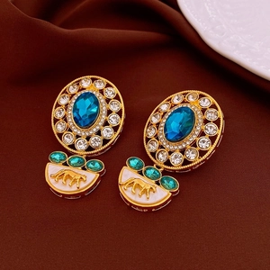 Detail of vintage earrings with blue stones, rhinestones and golden horse motifs