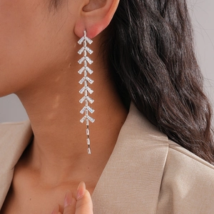 Close-up of elegant silver leaf tassel earrings with sparkling crystals on a model