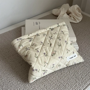 Detail of quilted corduroy makeup bag with floral print and a simple wish woven label