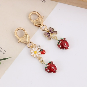 Close-up of strawberry keychains with red enamel, rhinestones, and cute daisy charms