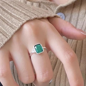 Close-up of 925 sterling silver ring with emerald-cut green stone on female hand