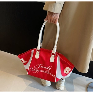 Detailed view of red canvas bowling bag with white embroidery held by model
