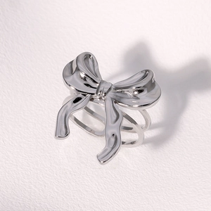 Detailed view of silver bow ring featuring fluid texture and layered multi-band design