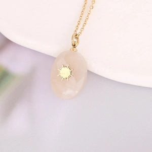 Close-up of pink natural stone pendant with gold starburst on stainless steel chain