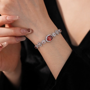 Detail of floral link bracelet with oval red gemstone and pavé white diamonds
