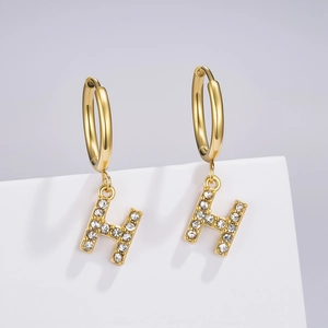 Detailed macro view of gold-tone H-letter earrings with shimmering micro-pave crystals