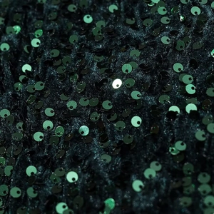 Macro shot of dark green sequins on evening dress fabric with shimmering texture