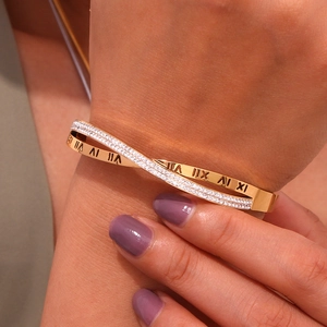Gold plated stainless steel criss-cross bangle with Roman numerals and zircons