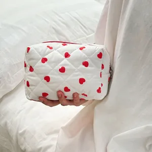 Quilted makeup bag with red heart pattern and zipper closure for cosmetic storage