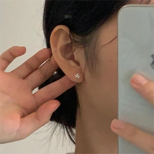 Star-shaped silver earring shown on the ear for a realistic minimalist minimalist look