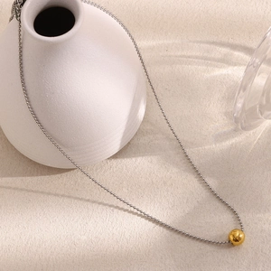 Close-up of minimalist stainless steel ball chain with polished gold bead pendant