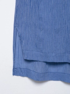 Détail du tissu à rayures bleues montrant l'ourlet fendu et la qualité des coutures