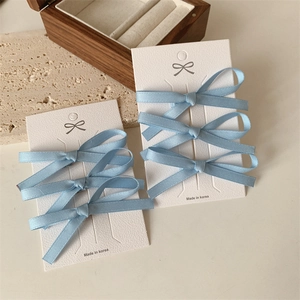 Set van drie lichtblauwe strik haarclips op witte kaart met houten achtergrond