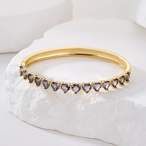 Luxurious 18K gold plated bangle with heart shaped purple zircons on white stone stand